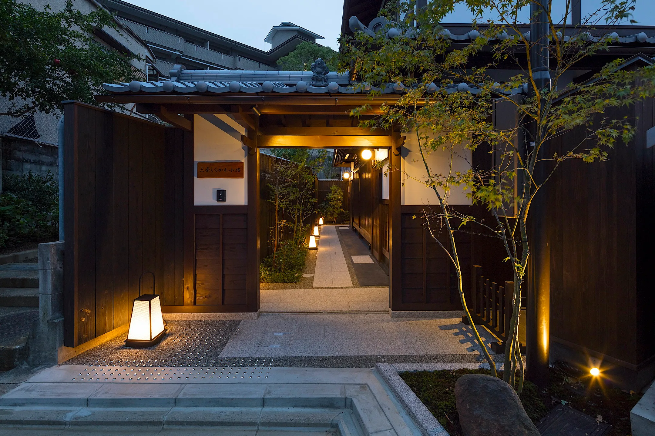 The lantern-lit entrance to a townhouse lane in Kyoto at dusk